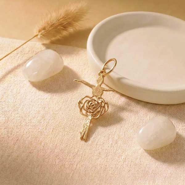 آویز طلا ۱۸ عیار طرح بالرین با دامن گل رز روی پس‌زمینه کرم و مینیمال.