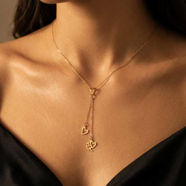 آویز طلا ۱۸ عیار با کلمه فارسی «تو» و قلب آویز روی پس‌زمینه گردن و لباس ساتن.
